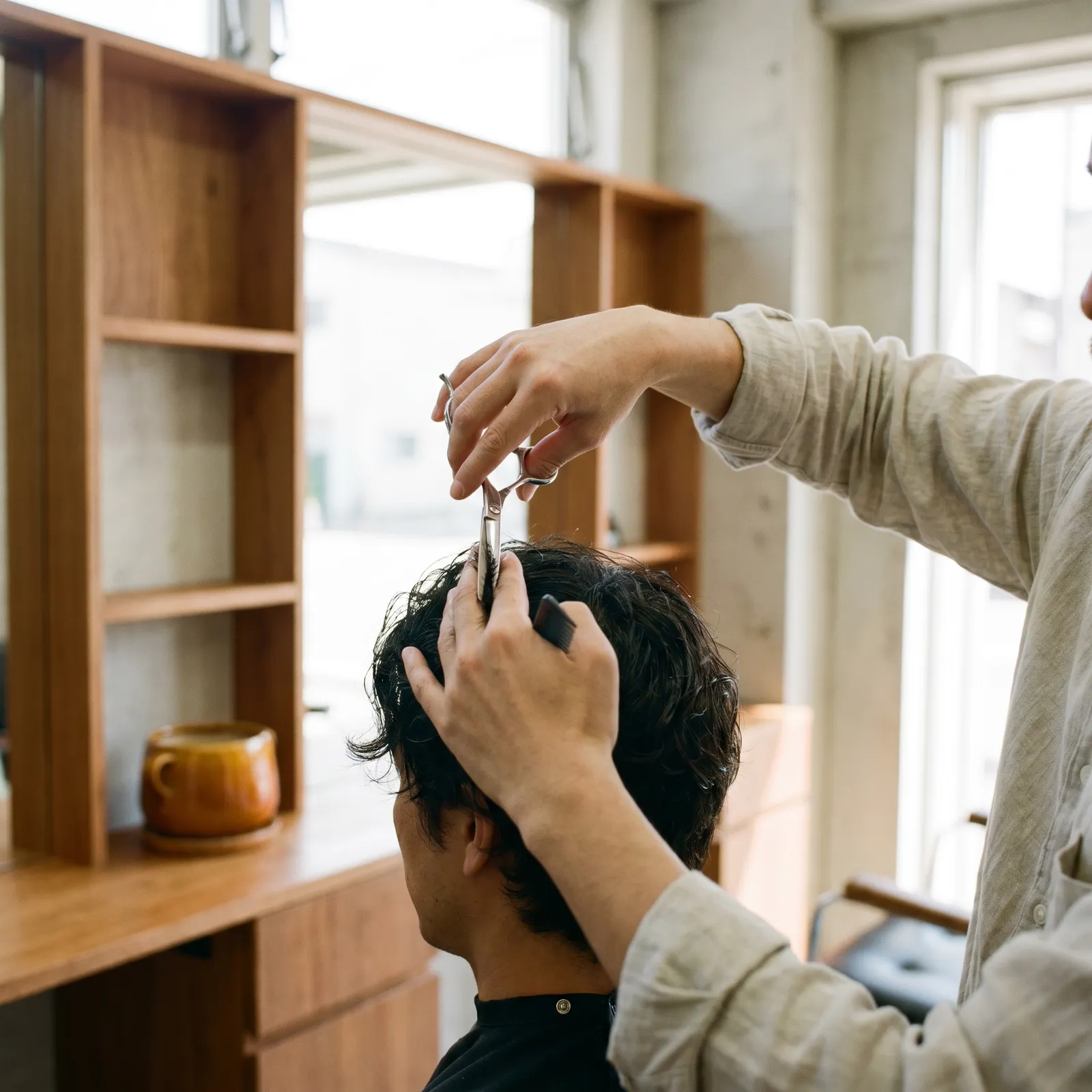 Barbier stylt mit Schere und Kamm, helle Atmosphäre, Detailaufnahme